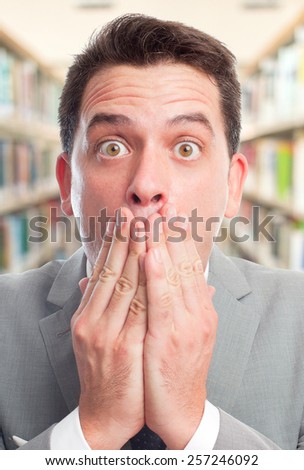 Business man with grey suit. He is looking scared. Over library background