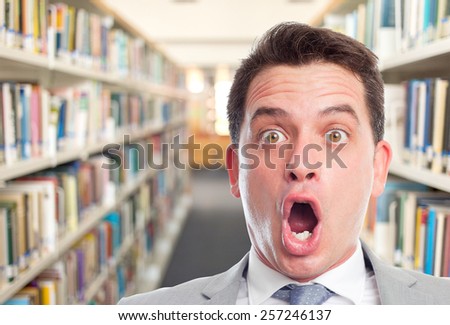 Business man with grey suit. He is looking surprised. Over library background