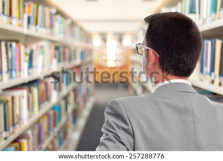 Business man with grey suit. He is showing his back. Over library background