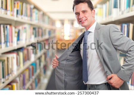 Business man with grey suit. He looks confident. Over library background