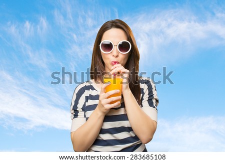 Woman with white sunglasses drinking a juice. Over clouds background