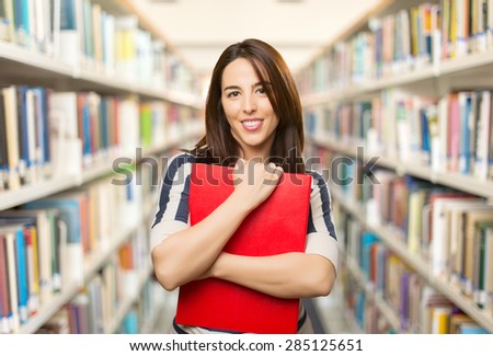 Smiling woman holding a red folder. Over library background