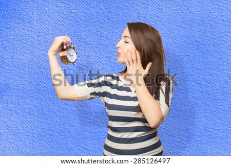 Quirky woman looking to a clock. Over blue background