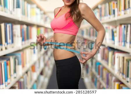 Fit young woman with a measurement scale. Over library background
