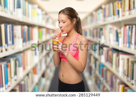 Woman drinking a orange juice. Over library background