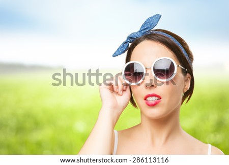 Pin up look woman with white sunglasses. Over nature bokeh background