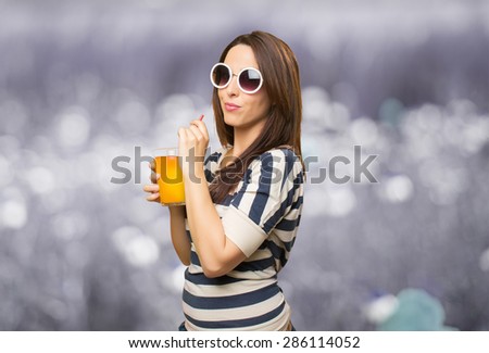 Woman with white sunglasses drinking a juice. Over abstract background