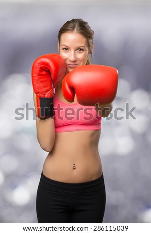 Young woman wearing gym clothes. She is ready to fight with her boxing gloves