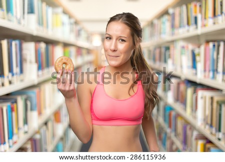 Young woman with a donut. Over library background