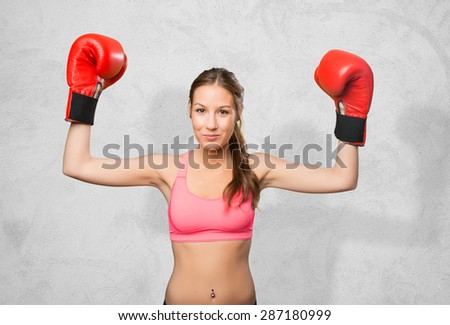 Young woman wearing gym clothes. She looks serious with her boxing gloves. Over concrete background