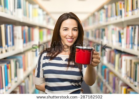 Smiling woman with a red cup. Over library background