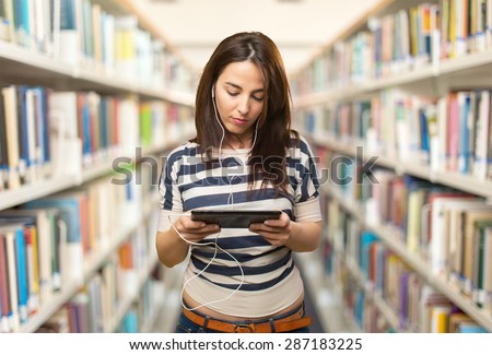 Serious woman using a tablet. Over library background