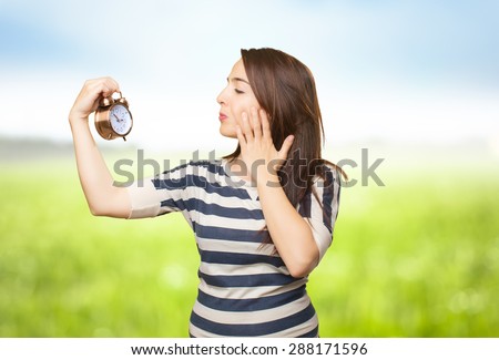 Quirky woman looking to a clock. Over nature bokeh background