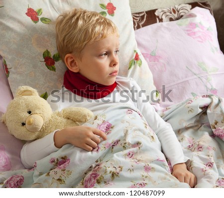 Sick boy is laying in bed with his teddy bear.