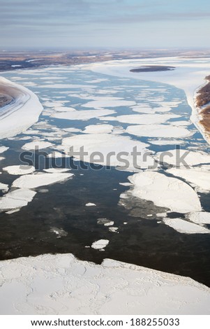 Aerial view of the great river with floating ice floes during spring day. Drifting of ice. Driving of ice. Ice floe. The Great Siberian river are vacating from ice.
