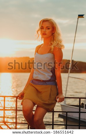 Beautiful blonde watches as the sun sets on the lake