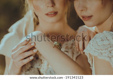 Twin sisters holding in his hand a green frog