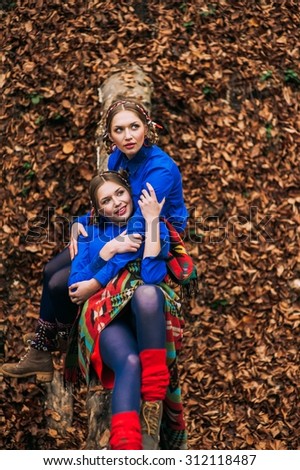 two beautiful blonde sisters twins in the autumn forest