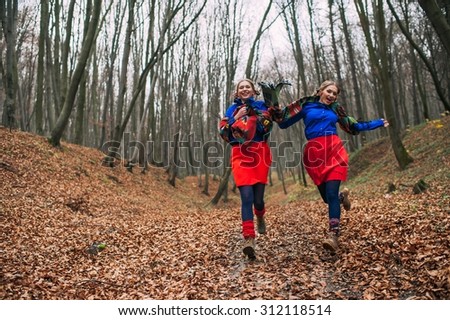 two beautiful blonde sisters twins in the autumn forest