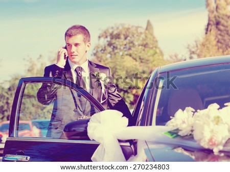 the groom speaks by phone near dressed up the wedding car
