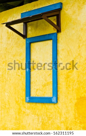 Closeup blue window frame on rusty yellow cement wall