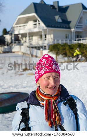 Portrait of a middle-aged woman on the background of the house in winter