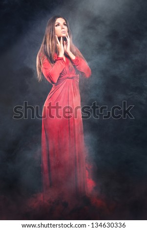 Fairy woman in red dress in smoke and fire.