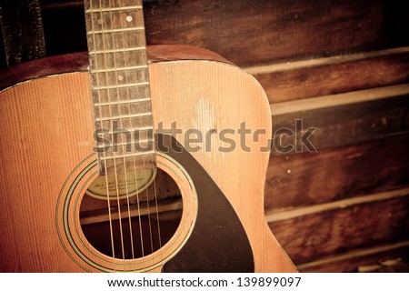 Old guitar with six strings close up.