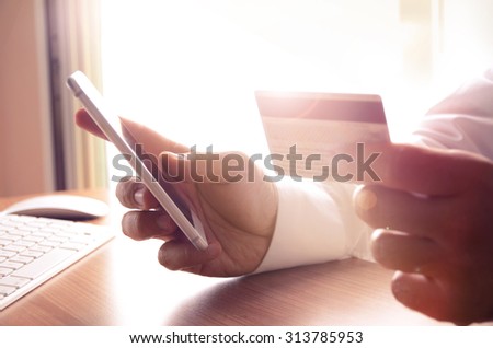 Closeup of man\'s hands holding credit cards and using mobile phone. Concept for m-commerce, online shopping, m-banking, internet security.