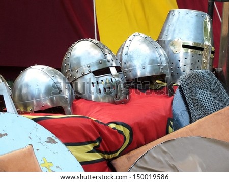 Row of silver metal knights helmets with banners and shields, used in medieval re enactments
