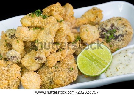 A basket of crispy chicken fingers with platter of vegetables and ranch dip on a white plate