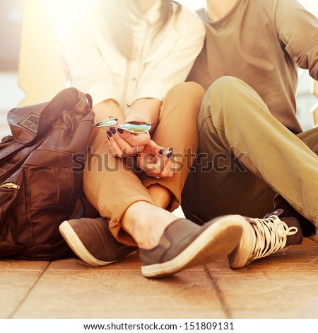 Young kissing happy couple in love sitting on the ground in summer sunny evening