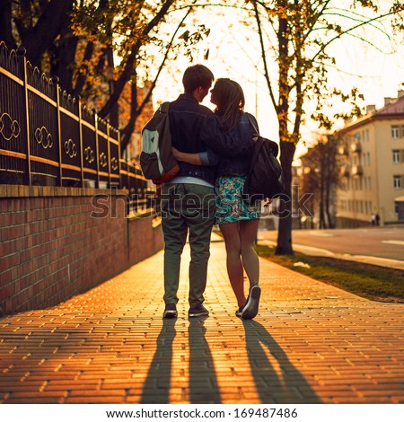 Young pretty colored portrait of young couple in love posing in evening in city and having fun together