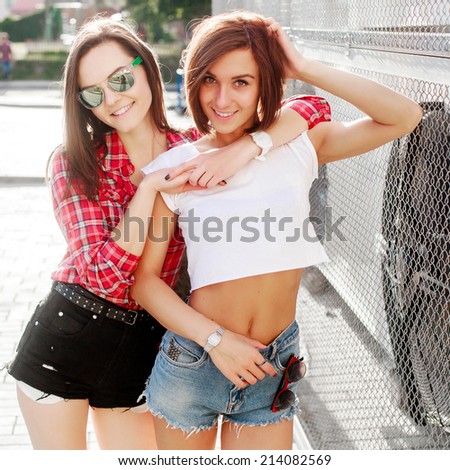 Outdoor closeup lifestyle portrait of two sexy pretty beautiful girls friends smiling in summer in love together on the street lesbian style