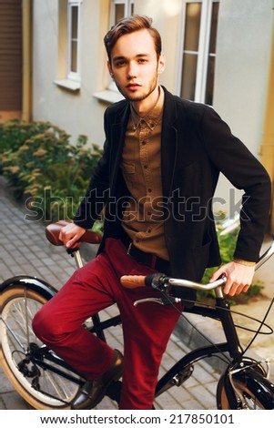 Young handsome fashion dressed man posing outdoor with vintage classic cruiser bicycle on the street autumn portrait