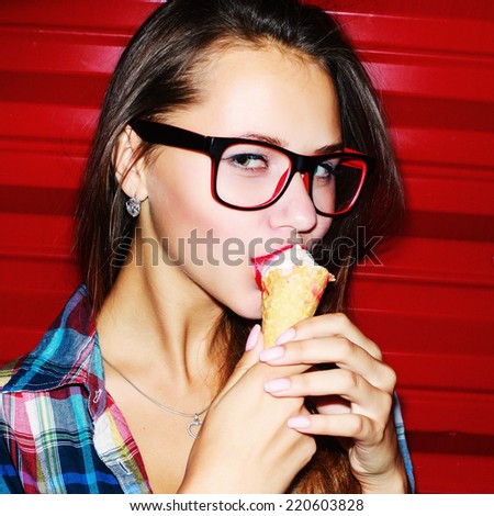 Fashion closeup portrait of pretty brunette girl with ice-cream and sensual look and red sexy lips eating with pleasure and having fun alone