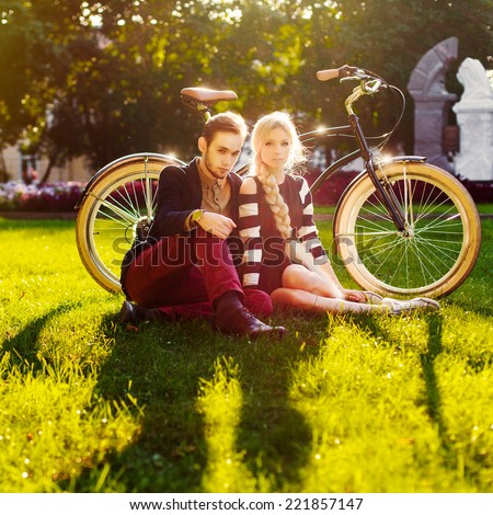 Young fashion sensual vintage couple in love posing outdoor in summer sitting on green grass in park with retro bicycle and have fun alone