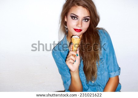 Indoor closeup fashion portrait of pretty young hipster brunette woman with ice-cream and sexy red lips looks really cute in jeans outfit