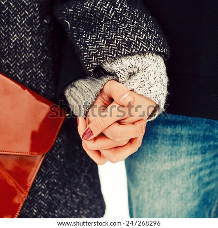 Closeup photo of two hands of young couple in love in winter cold weather stylish hipster clothing