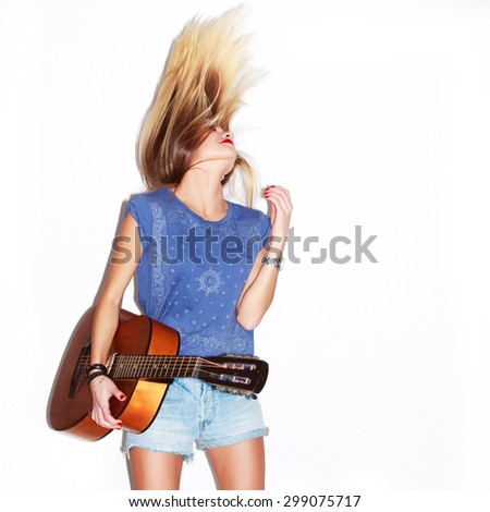 Young active dancing happy musician woman posing with guitar and long blonde hairs