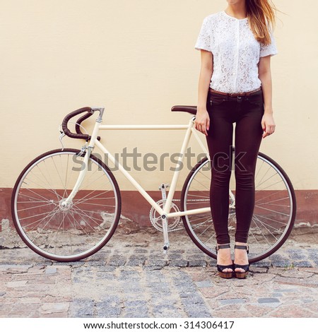 Pretty young blonde hipster girl posing outdoor in city with old fashion vintage bicycle near yellow wall have fun outdoor