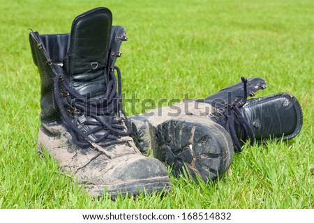 DEN HAAG, NETHERLANDS - OCTOBER 09, 2012: Dutch army boots model M90 / M400 black leather boot covered in mud standing on grass.