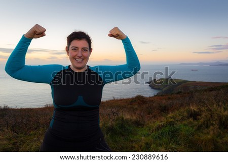 Smiling woman looking into the camera wearing a sports outfit showing her muscles