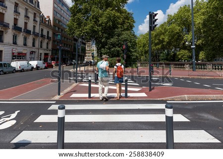 TOULOUSE, FRANCE - JULY 27, 2014: 2 locals crossing a zebra crossing. French government is trying to improve matters but French drivers still pay little attention to pedestrians and zebra crossings.