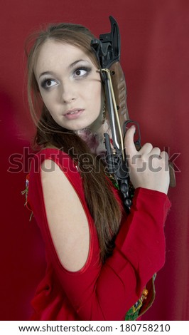 Young girl with a crossbow in the original dress on red background