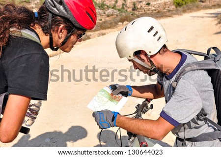 Two cyclist men read the map on the bicycle trail