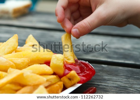 child dipping a fried chip into tomato sauce