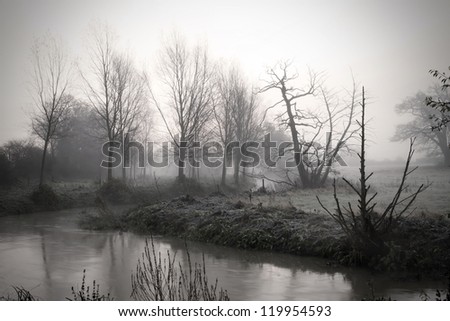 calm river running through misty fields