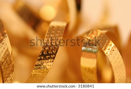 Close up of loops of gold metallic ribbon with a soft, blurred background