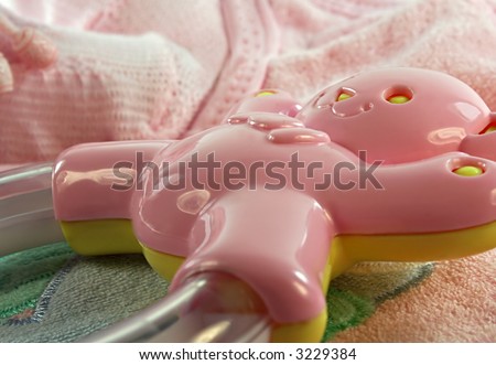 A pink and yellow baby rattle with other baby things.